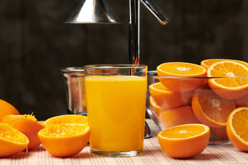 Squeezing an orange with a manual press, close view, making a glass of fresh. Fresh oranges on a wooden table, whole, squeezed and sliced.