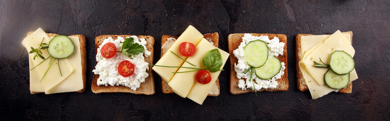 rolled slices of golden gouda cheese or cream cheese on a sandwich garnished with sliced cucumber and herbs. bread or toast with cheese for breakfast