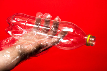 Hand in plastic or rubber disposable glove holds plastic transparent bottle of carbonated drink. Zero waste, sorting garbage,reusable containers.ecology environment protection and coronavirus concept.