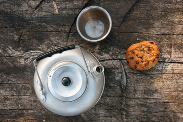 Aluminum teapot , cup and oatmeal cookies with chocolate on dry wooden table. Flat lay food. Picnic. Outdoor cooking. Kettle. Picnic concept