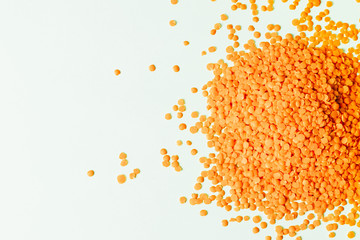 Orange lentils nicely laid out on a white background. Top view. Vegetarian food. Greenish background