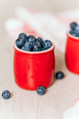 fresh blueberries in red pots on a wooden background, on a drop of water berries. healthy nutrition, vitamin charge, summer berries