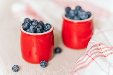fresh blueberries in red pots on a wooden background, on a drop of water berries. healthy nutrition, vitamin charge, summer berries