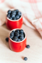 fresh blueberries in red pots on a wooden background, on a drop of water berries. healthy nutrition, vitamin charge, summer berries