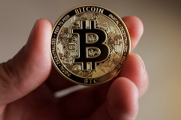 Man Holding Bitcoin In His Hand. Bitcoin Shows On Screen. Close Up shot