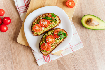 toasted bread with avocado paste and fresh tomato. Avocado mixed with lemon juice is spread on bread.  health food concept, vegan, vegetarian