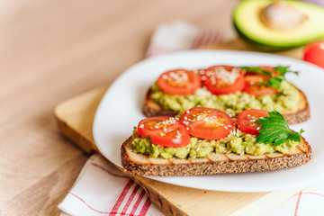 toasted bread with avocado paste and fresh tomato. Avocado mixed with lemon juice is spread on bread.  health food concept, vegan, vegetarian
