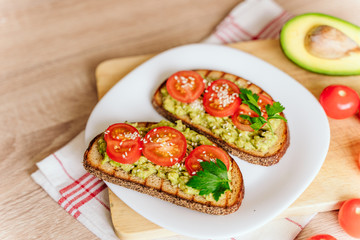 toasted bread with avocado paste and fresh tomato. Avocado mixed with lemon juice is spread on bread.  health food concept, vegan, vegetarian