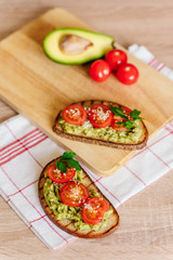 toasted bread with avocado paste and fresh tomato. Avocado mixed with lemon juice is spread on bread.  health food concept, vegan, vegetarian