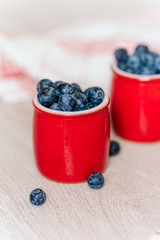 fresh blueberries in red pots on a wooden background, on a drop of water berries. healthy nutrition, vitamin charge, summer berries