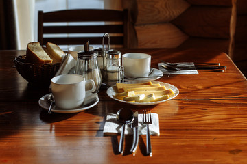breakfast table with mugs and appliances butter cheese and bread