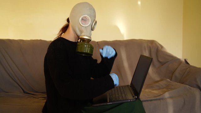 white girl in gas mask works from home on a computer