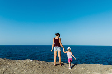 mother and daughter look at the sea from the shore