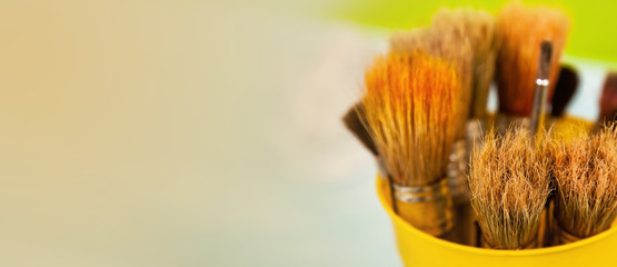 A set of brushes for painting with paints. Many brushes in a yellow metal stand