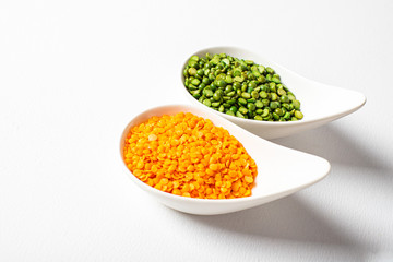 two types of legumes, beautifully arranged in cups and on a white background - green peas and orange lentils. Top view. copy space. Vegetarian food.