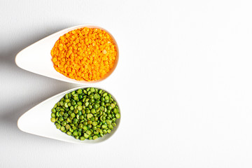 two types of legumes, beautifully arranged in cups and on a white background - green peas and orange lentils. Top view. copy space. Vegetarian food.