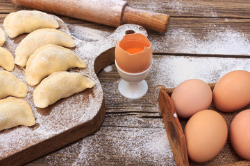 Baking cake in rural kitchen - dough recipe ingredients eggs, flour, milk, butter, sugar on vintage wooden table from above. Background layout with free text space.