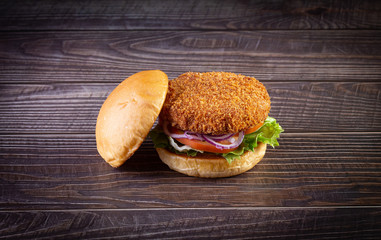 Chicken burger with lettuce, tomato, purpple onion and handmade mayo on the wood table. Delicious.