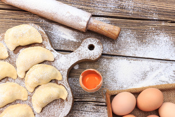 Baking cake in rural kitchen - dough recipe ingredients eggs, flour, milk, butter, sugar on vintage wooden table from above. Background layout with free text space.