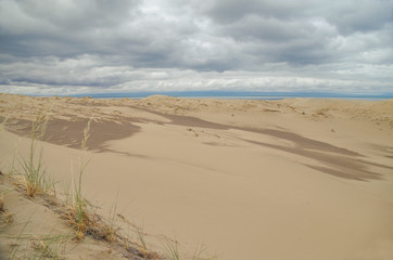 Dramatic clouds over the sand dunes at morning. Barkhan Mongol-Els sands on the coast of saltwater lake Dorgon. Nature and travel. Mongolia, Gobi Desert, Govi-Altai