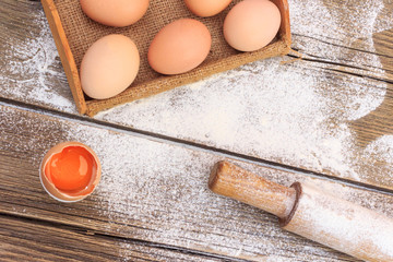 Background with flour and eggs on a wooden table