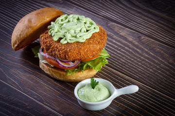 Chicken burger with lettuce, tomato, purpple onion and handmade mayo on the wood table. Delicious.