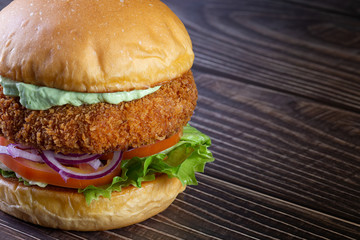 Chicken burger with lettuce, tomato, purpple onion and handmade mayo on the wood table. Delicious.