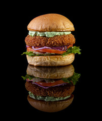 Chicken burger with lettuce, tomato, purpple onion and handmade mayo on black backgorund. Delicious.