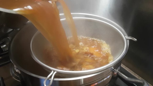 Preparation of bisque sauce. Tomato paste is added to the broth with prawns and mixed