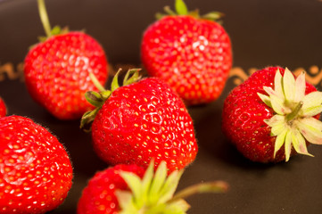 fresh ripe berries strawberries on black ceramic plate, close up