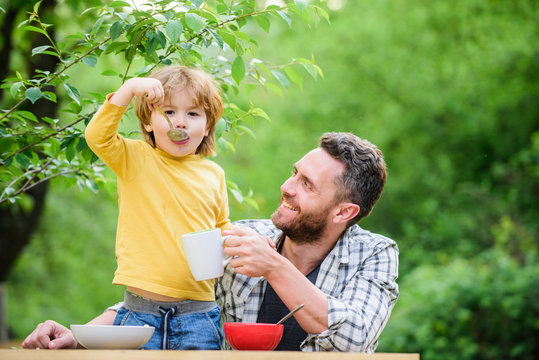 Family Enjoy Homemade Meal. Father Son Eat Food And Have Fun. Food Habits. Little Boy With Dad Eating Food Nature Background. Summer Breakfast. Healthy Food Concept. Feeding Baby. Menu For Children