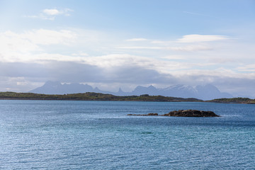 Norwegian fjord and mountains surrounded by clouds, ideal fjord reflection in clear water. selective focus.