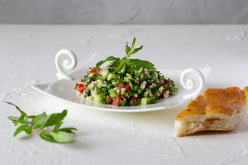 Tabbouleh salad and bread.  Vegetarian salad with bulgur wheat, chopped tomato, cucumber, parsley and mint. Lebanese and Middle Eastern cuisine.