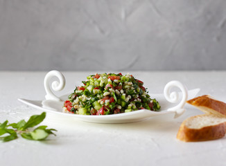 Tabbouleh salad and bread.  Vegetarian salad with bulgur wheat, chopped tomato, cucumber, parsley and mint. Lebanese and Middle Eastern cuisine. Copy space