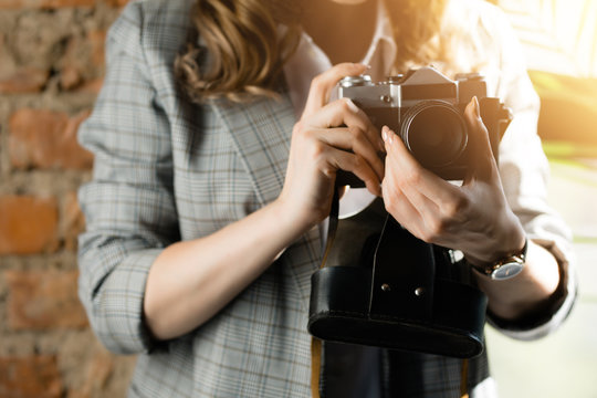 A woman in a checkered jacket takes photos on a film vintage retro camera. The sun's rays in the photo.
