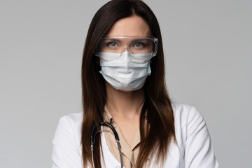 Doctor / nurse smiling behind surgeon mask. Closeup portrait of young caucasian woman model in white medical scrub