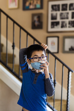 Little boy adjusting straps on face mask at home