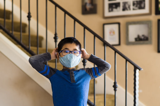 Asian boy tying strings on cloth mask