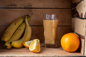 Fresh juice from banana and orange. Juice and fruits in a wooden box.