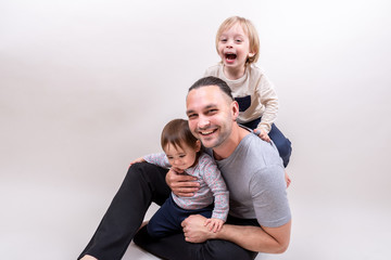 Young father playing with happy laughing kids sitting on the floor during Father's day
