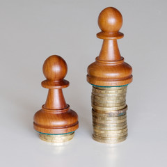 Two pawns chess pieces on columns of coins, symbolizing a sharp income inequality