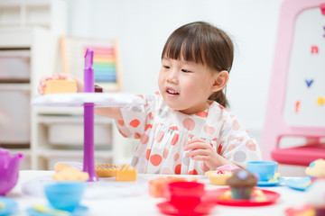 toddler girl prerend play preparing tea party at home