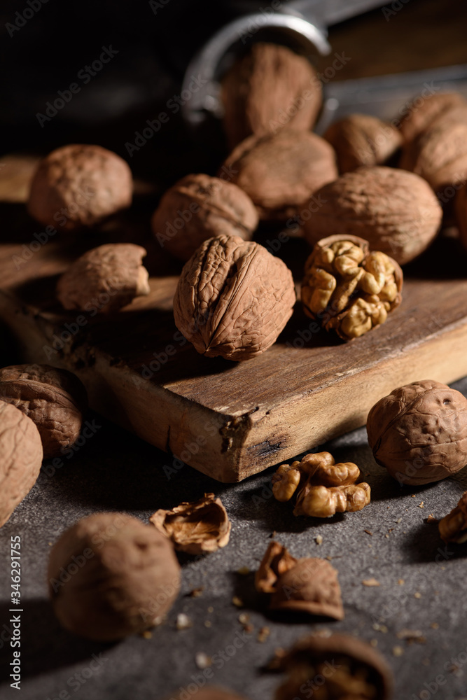 Wall mural walnuts and walnut kernels on an old wooden board near the nutcracker. dark background.