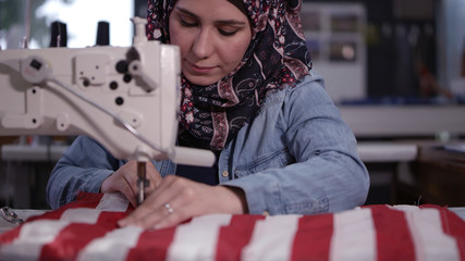 Woman sewing American flag feeding it through the machine.