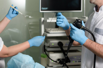 Endoscopic examination of a patient in a hospital. Doctor and nurse holding a gastroscopy instrument in hand