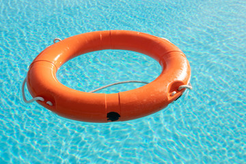 Orange lifebuoy floating on a pool