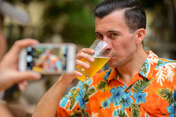 Happy multi ethnic tourist couple taking picture with phone at restaurant