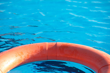 Fototapeta na wymiar Orange lifebuoy floating on a pool