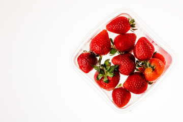 Fresh strawberries in water in plastic dishes on a white background with a copy space. The view from the top