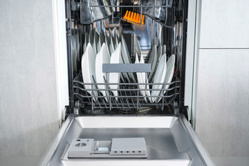 Open dishwasher with clean dishes in the home kitchen, front view.